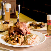 Hellers Brauhaus Ein gedeckter Tisch mit verschiedenen deftig mächtigen Speisen und ein Glas Kölsch-A table set with a variety of hearty dishes and a glass of Kölsch beer.
