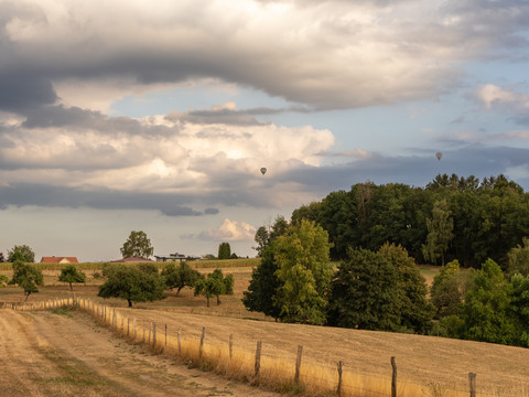 Bierweg Landschaft mit grünen Feldern, Wald, Hügeln und Heißluftballons am Himmel bei Wiehl.