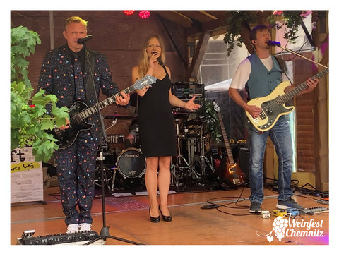 Występ na żywo zespołu z wokalistą i muzykami na scenie podczas festiwalu wina w Chemnitz.