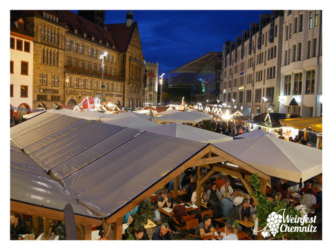 P1160905_Rahmen.jpg Weinfest auf einem belebten städtischen Platz mit vielen Besuchern und Verkaufsständen.