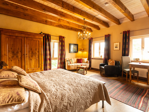 Ferienwohnung Hof Tüschenbonnen Gemütliches Schlafzimmer mit Holzbalkendecke, Doppelbett, antikem Schrank und großem Fenster.