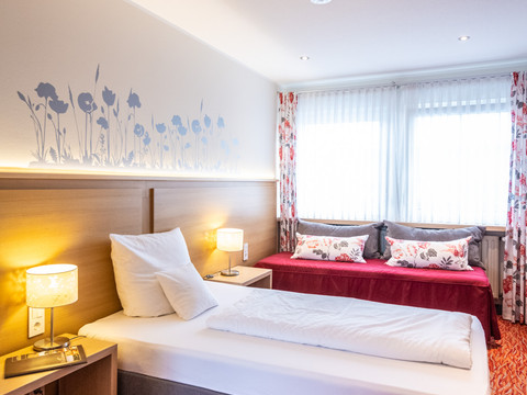Landhotel Napoleon ```html <p>Hell eingerichtetes Doppelzimmer mit Einzelbett, Sofa und floral dekorierter Wand in Wipperfürth.</p> ```
