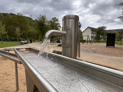 Wasserspielplatz im Kurpark Wasserspielplatz mit Edelstahlpumpen und schmalen Wasserkanälen in einer grünen Parkanlage.
