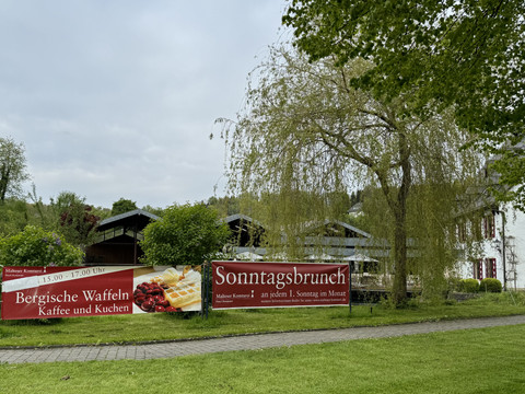 Banner - Bergische Waffeln Im Bild ist ein charmantes ländliches Café mit Schildern zu bergischen Waffeln und Sonntagsbrunch.