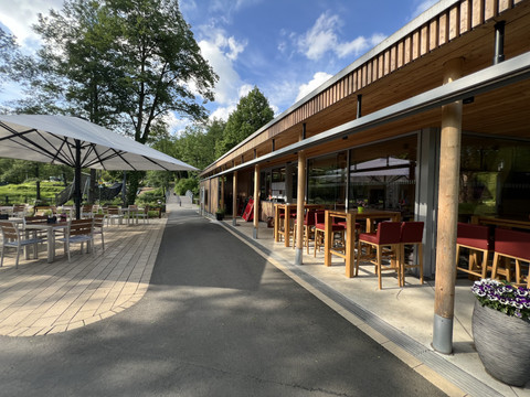 Bistro im Wiehlpark <p>Ein Café mit Terrasse, roten Hochstühlen und Tischen im Freien, unter großen Sonnenschirmen.</p>