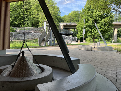 Grillplatz im Wiehlpark <p>Moderner Platz mit geometrischen Betonbänken, Skulpturen und grünem Hintergrund unter Brücken.</p>