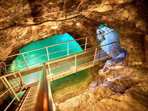 Unterirdischer See im Marie Louise Stolln Metallbrücke überspannt türkisfarbenen See in natürlichen, von Felsen umgebenen, unterirdischem Raum.