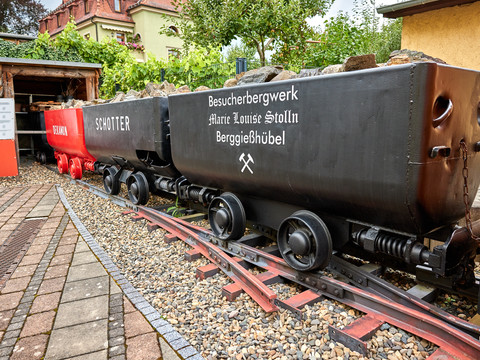 Historische Bergwerkslore auf Schienen vor einem farbenfrohen Gebäude im Freien ausgestellt.