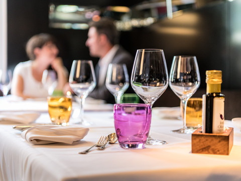 Hotel Zur Post Ein gedeckter Tisch in einem eleganten Restaurant, mit Paar im Hintergrund unscharf zu sehen.