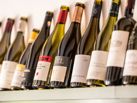 Hotel Zur Post Weinflaschen in verschiedenen Sorten und Größen, schräg auf einem Regal stehend.