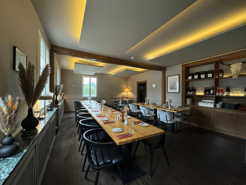 Zum Haus Olpe - Innenansicht  Gemütliches Restaurant mit langen Holztischen, schwarzem Mobiliar und stimmungsvoller Beleuchtung.