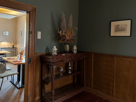 Zum Haus Olpe - Innenansicht separater Raum Dekoration Ein eleganter Essbereich in Holzoptik mit antikem Sideboard, stilvoll dekoriert mit Trockenblumen und Kerzen.
