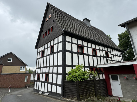 Haus Steeg Fachwerkhaus mit schwarz-weißer Fassade und rotem Rahmen, gelegen an einer ruhigen Straße.