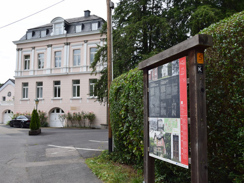 Hoffnungsthaler Hammer Klassizistische Villa mit Infotafel im Vordergrund, umgeben von Bäumen, gelegen in Rösrath.