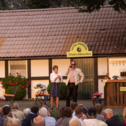 Piumer Bauerntheater - Schauspiel.jpg Open-Air-Theateraufführung vor einem Fachwerkhaus, Publikum sieht zwei Schauspielern in Kostümen zu.