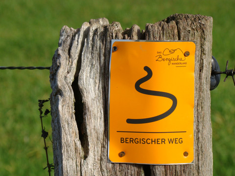 Bergischer Weg Etappe 6 <p>Ein Holzpfahl mit einem gelben Schild markiert den Fernwanderweg "Bergischer Weg".</p>