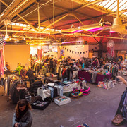 Fair Trödeln market in Cologne Ein Trödelmarkt in großer Halle: Besucher schlendern zwischen Ständen mit Kleidung, Dekoration und Kunsthandwerk in einer warmen, beleuchteten Atmosphäre.A flea market in a large hall: visitors stroll between stalls selling clothes, decorations and handicrafts in a warm, illuminated atmosphere.