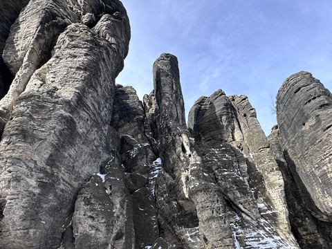Tyssaer Wände Hohe, zerklüftete Felsformationen mit vereinzelten Schneeresten vor einem klaren blauen Himmel.