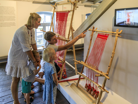 Eine Familie betrachtet traditionelle Webrahmen in einem Museum.