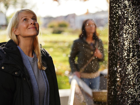 Erlebniskurpark in Bad Laer Zwei Frauen betrachten fasziniert einen glitzernden Wasserfall im Freien.Two women are fascinated by a glittering outdoor waterfall.To kvinder fascineres af et glitrende udendørs vandfald.Twee vrouwen zijn gefascineerd door een glinsterende waterval in de buitenlucht.