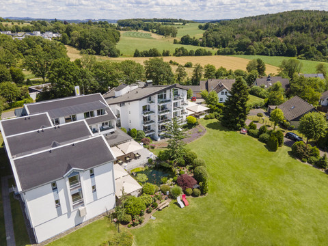 Derichsweiler Hof Luftaufnahme eines weißen Wohngebäudekomplexes mit gepflegtem Garten in einer ländlichen Umgebung.