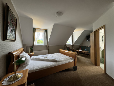 Haus Thal - Zimmer 2 Ein gemütliches, helles Hotelzimmer mit Dachschrägen, Doppelbett und Sitzbereich. Fenster bieten Aussicht.