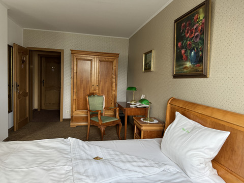 Haus Thal - Zimmer 2 Gemütliches Hotelzimmer mit Holzmöbeln, einem Bett, einem Tisch, künstlerischen Gemälden an den Wänden.