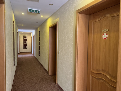 Haus Thal - Ansicht Flur Ein beleuchteter Hotelflur mit Holztüren, Teppichboden und einem Notausgangsschild an der Decke.