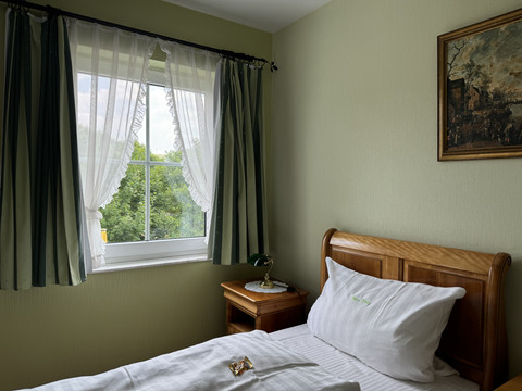 Haus Thal - Zimmer 1 Helles, gemütliches Einzelzimmer mit Holzbett, kleinem Nachttisch, Bild an der Wand, Blick ins Grüne.