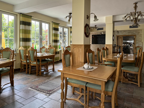 Haus Thal - Ansicht Restaurant Innenbereich Einladendes, gemütliches Restaurant-Interieur mit Holztischen, grünen Stühlen und großen Fenstern.