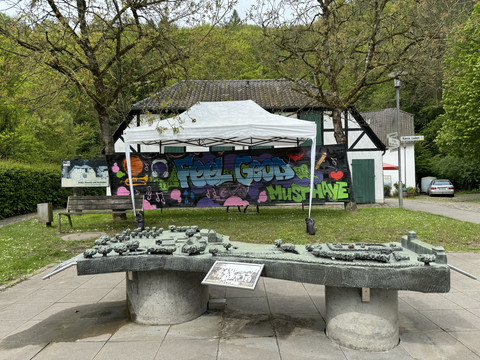 Papiermuseum Kunstinstallation im Freien mit Graffiti-Sprüchen, mitten in einem idyllischen, bewaldeten Gebiet.