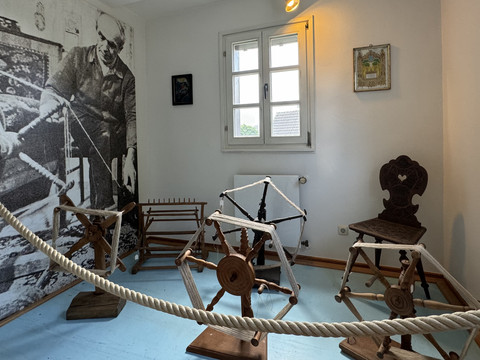 Bergisches Museum für Bergbau, Handwerk und Gewerbe  Ein Raum im Museum zeigt alte Spinnräder und Webgeräte vor einem historischen Schwarzweiß-Foto.