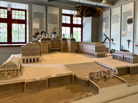 Modell - Schloss Bensberg  Ein maßstabsgetreues Modell eines historischen Schlosses in einem Museumsraum mit roten Fenstern.