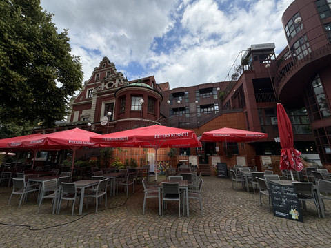 Bergischer Löwe Ein gemütlicher Außenbereich eines Restaurants mit roten Sonnenschirmen und leeren Tischen.