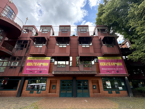 Bürgerhaus Bergischer Löwe - Frontalansicht Modernes Gebäude des Bürgerhauses Bergischer Löwe mit markanter Fassade und Werbebannern.