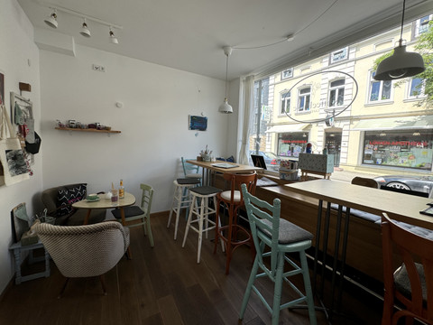 Kaffeepause - Innenansicht Gemütliches Café mit bunten Stühlen und heller Fensterfront. Straßenszene spiegelt sich im Fenster.