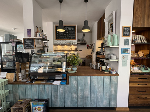 Kaffeepause - Innenansicht Gemütliches Café mit rustikalem Tresen, Gebäck unter Glas und freundlicher, einladender Atmosphäre.