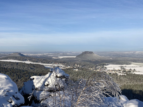 Blick vom Papststein zum Gohrisch und Lilienstein Verschneite Berglandschaft der Sächsischen Schweiz mit Gohrisch und Lilienstein unter blauem Himmel.Snow-covered mountain landscape of Saxon Switzerland with Gohrisch and Lilienstein under a blue sky.Zasněžená horská krajina Saského Švýcarska s městy Gohrisch a Lilienstein pod modrou oblohou.Pokryty śniegiem górski krajobraz Szwajcarii Saksońskiej z Gohrisch i Lilienstein pod błękitnym niebem.Besneeuwd berglandschap van Saksisch Zwitserland met Gohrisch en Lilienstein onder een blauwe hemel.Paesaggio montano innevato della Svizzera sassone con Gohrisch e Lilienstein sotto un cielo azzurro.
