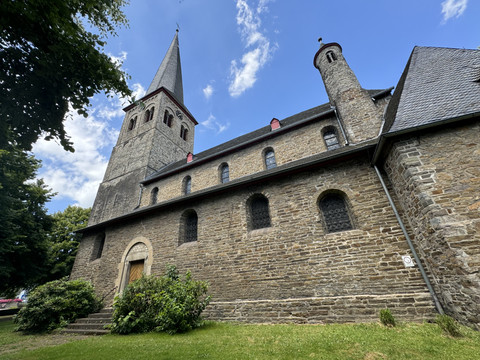 Kirche St. Walburga Die Aufnahme zeigt eine historische Kirche mit steinernem Mauerwerk, hohem Turm und blauem Himmel.