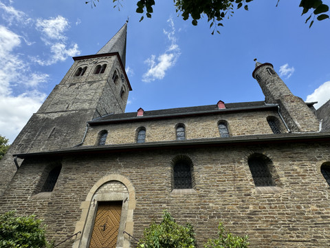 Kirche St. Walburga Historische Kirche mit steinernen Mauern, markantem Turm und schrägem Dach unter blauem Himmel.