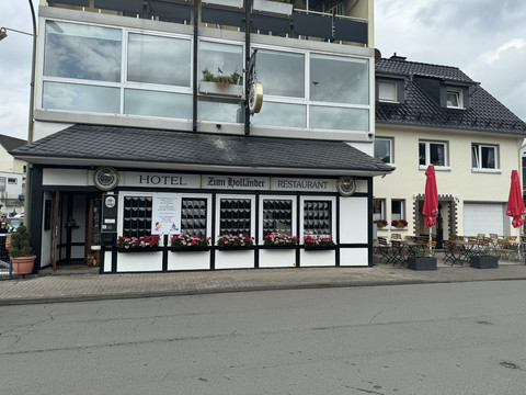 Hotel-Restaurant Zum Holländer - Außenansicht Hotel und Restaurant mit schwarzen Fensterläden und bunten Blumenkästen, angrenzendem Außenbereich.