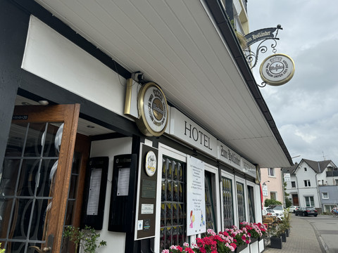 Hotel-Restaurant Zum Holländer - Außenansicht Hotelgebäude im Fachwerkstil mit Blumen und traditionellen Schildern. Hintergrund zeigt eine Straße.