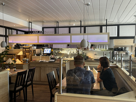 Restaurant Zum Holländer - Innenansicht <p>Modernes, gemütliches Restaurant mit Holzmöbeln und stilvoller Beleuchtung, zwei Personen im Gespräch.</p>