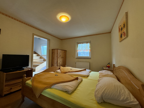 Gasthof Zum Stausee Gemütliches Schlafzimmer mit Doppelbett, Holzmöbeln, einem Fernseher und hellem Fensterlicht.