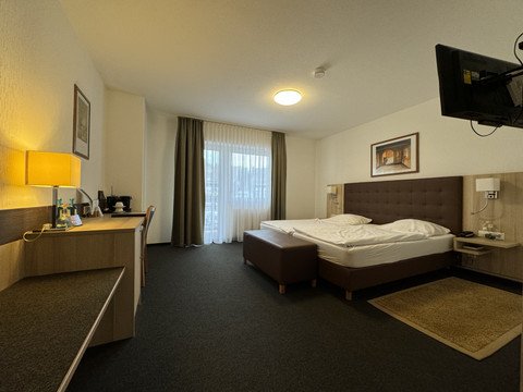 Hotel-Restaurant Zum Holländer - Doppelzimmer Wohnliches Hotelzimmer mit Doppelbett, Schreibtisch, TV und Fenster mit hellen Vorhängen.