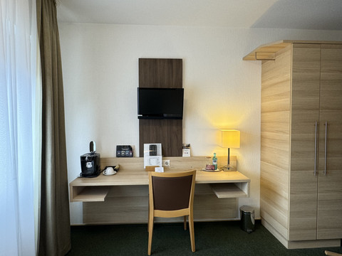 Hotel-Restaurant Zum Holländer - Ansicht Einzelzimmer Arbeitsbereich in einem Hotelzimmer mit Stuhl, Schreibtisch, TV, Lampe und Kaffeemaschine.