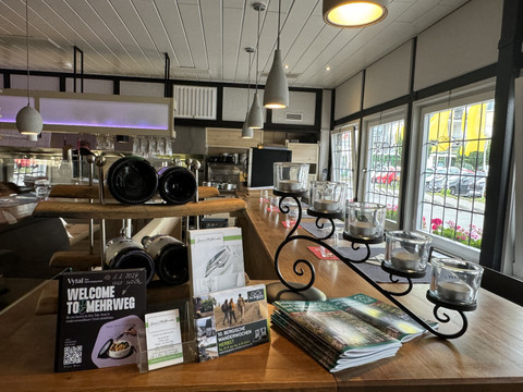 Restaurant Zum Holländer - Innenansicht Weinregale, Broschüren und Teelichter auf einer hölzernen Bar im stilvollen Innenraum eines Restaurants.