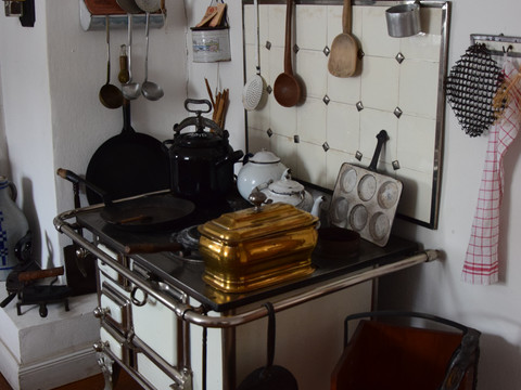 Bauernhofmuseum Ein nostalgischer Küchenherd mit alten Kochutensilien und einem Holzvorrat in gemütlicher Atmosphäre.