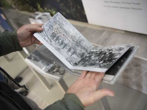 Bergisches Grauwacke-Museum Zwei Hände halten ein aufgeschlagenes Buch mit historischen Schwarz-Weiß-Fotos von Menschenansammlungen.