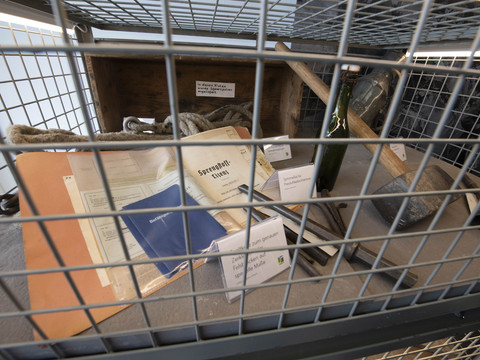 Bergisches Grauwacke-Museum Objekte hinter einem Käfig in einem Museum, darunter ein Seil, alte Dokumente und Werkzeuge.